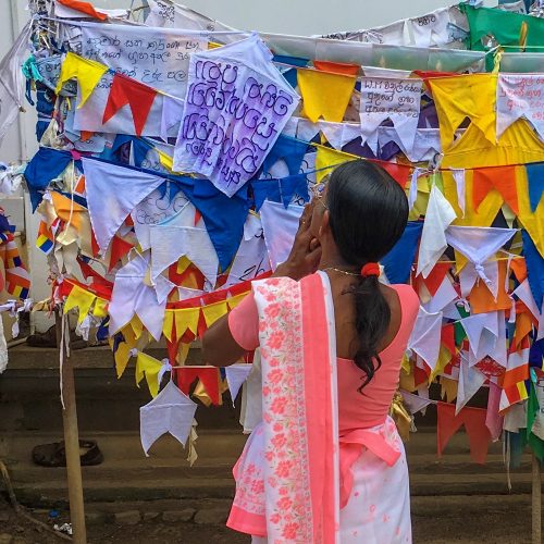 Mulher a pendurar bandeiras de oração do Budismo no Sri Lanka