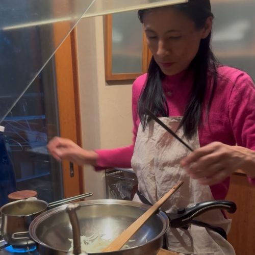 Mulher jjaponesa a cozinhar com tachos e utensílios