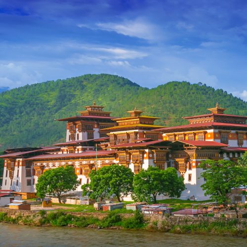 Vista para Dzong no Butão com céu azul e verde das montanhas por trás