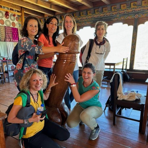 Seis mulheres portuguesas de um grupo da Macro Viagens seguram divertidas um falo no Butão.