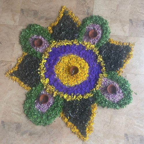 Mandala de flores verdes, roxas e amarelas, feita no chão
