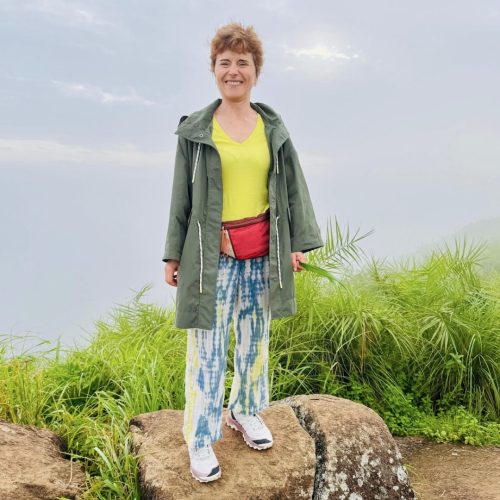Senhora ocidental posa para foto de costas para uma paisagem de montanha, em Kerala