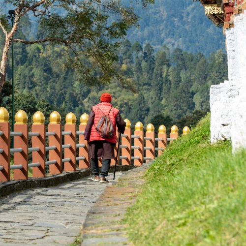 Butanês a passear por um caminho junto a um mosteiro no Butão