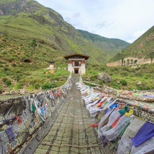 Vista para ponte pedonal de ferro no butão, está cheia de bandeiras tibetanas