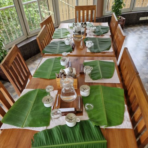 Vista para mesa com folhas de bananeira varias, onde vão servir o almoço que será sadhya