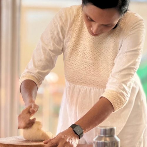 Senhora Indiana vestida de branco ensina a fazer chapatis num showcooking no retiro ayurveda