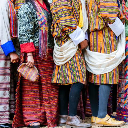 vista de pormenor dos trajes tradicionais butaneses (homens e mulheres com padrões típicos coloridos)