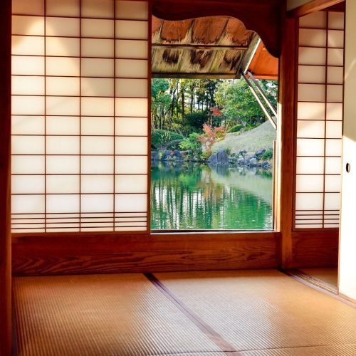 Sala típica japonesa com uma janela aberta que mostra um lado e um cenário de natureza verde