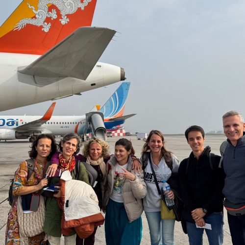 grupo de viajantes junto a um avião no aeroporto do Butão, acabaram de desenbarcar e estão sorridentes